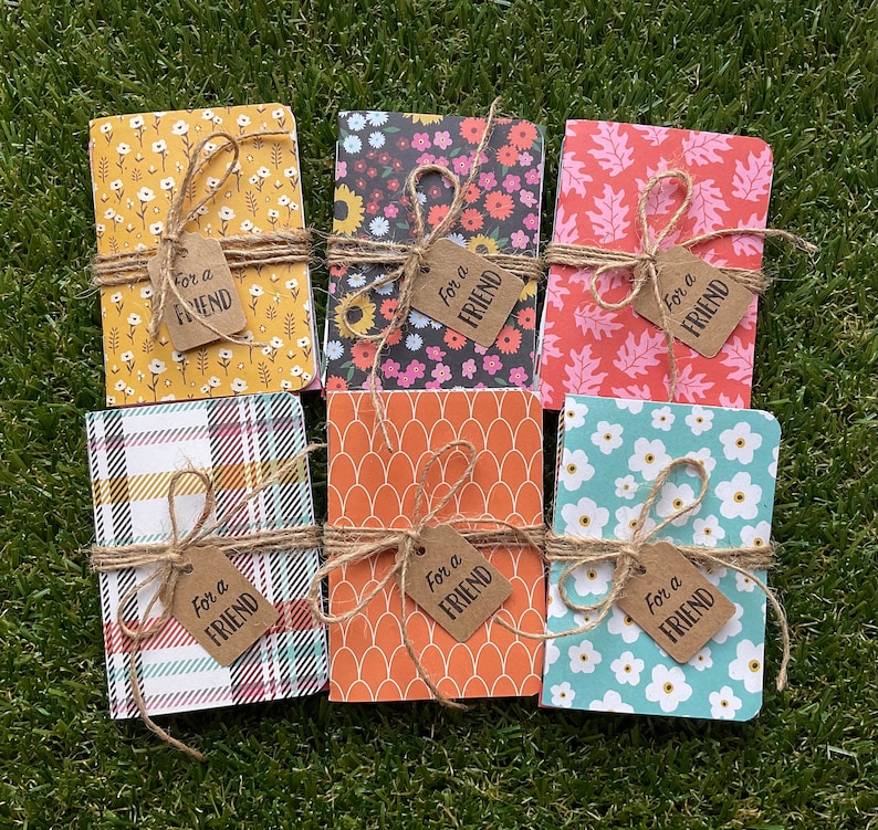 May include: Six small notebooks with different patterned covers. Each notebook is tied with twine and has a brown tag that says "For a Friend".