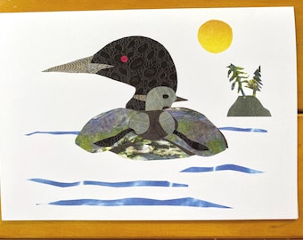 May include: A black and gray loon with a red eye swims in blue water with a small island and a yellow sun in the background.