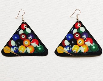 May include: A pair of triangle-shaped earrings with a colorful image of a pool table with billiard balls and a cue stick. The earrings are made of wood and have silver hooks.