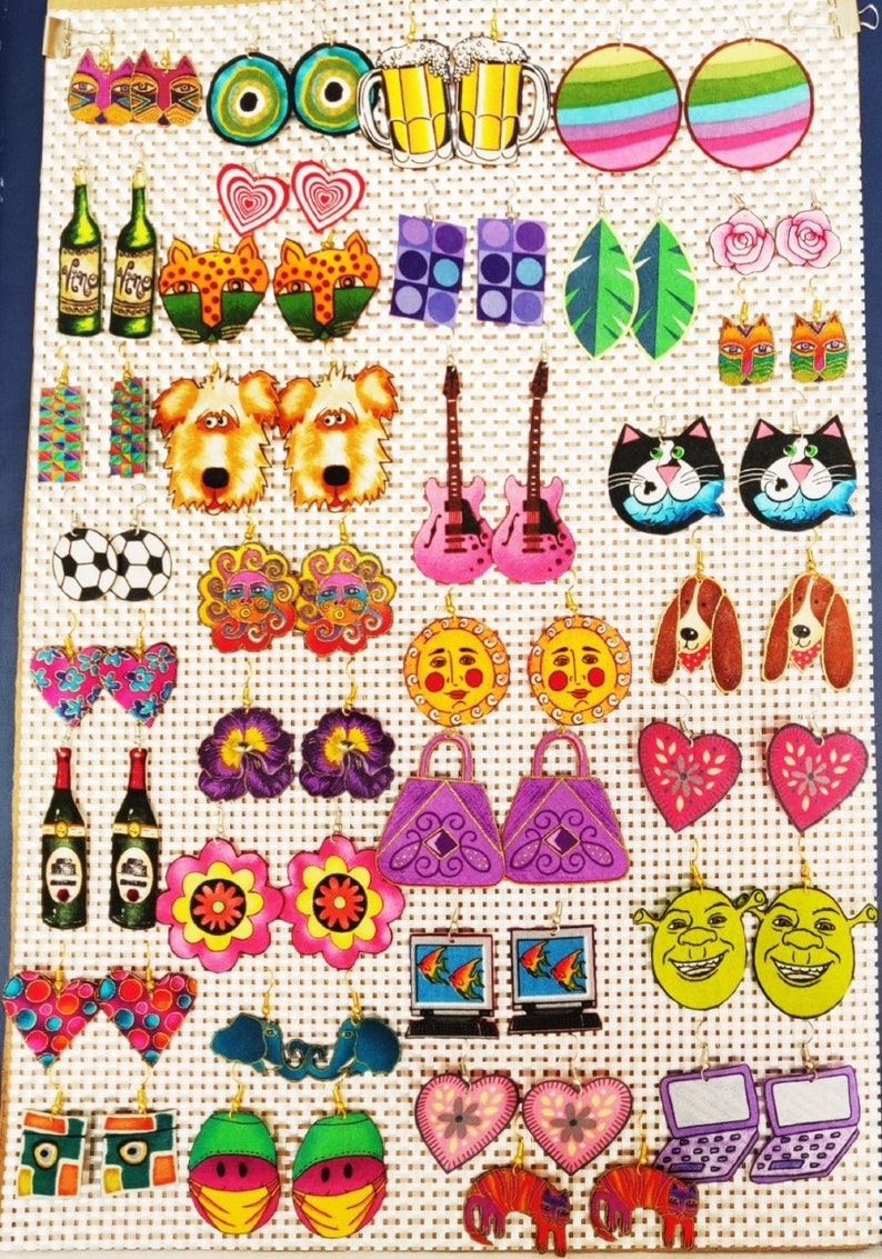 Pode incluir: Uma cole&ccedil;&atilde;o de brincos de madeira pintados &agrave; m&atilde;o e coloridos. Os brincos apresentam v&aacute;rios desenhos, incluindo gatos, c&atilde;es, guitarras, flores, cora&ccedil;&otilde;es e muito mais.