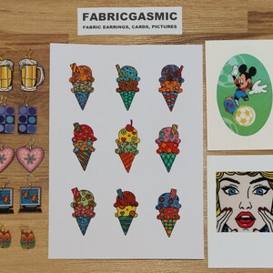 Pode incluir: Um conjunto de brincos de tecido coloridos com cones de sorvete, canecas de cerveja e personagens de desenhos animados. Os brincos s&atilde;o feitos &agrave; m&atilde;o e v&ecirc;m em uma variedade de designs. O texto "FABRICGASMIC" e "FABRIC EARRINGS, CARDS, PICTURES" est&aacute; impresso em um cart&atilde;o branco.