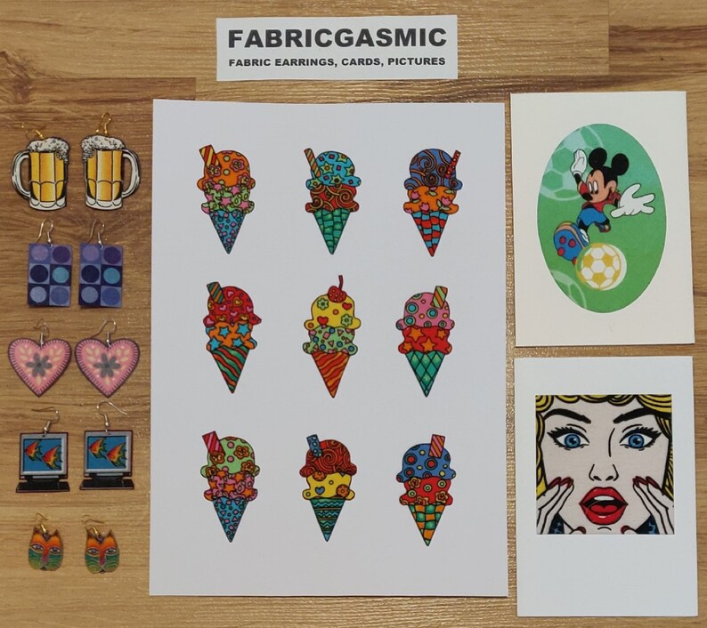 Pode incluir: Um conjunto de brincos de tecido coloridos com cones de sorvete, canecas de cerveja e personagens de desenhos animados. Os brincos s&atilde;o feitos &agrave; m&atilde;o e v&ecirc;m em uma variedade de designs. O texto "FABRICGASMIC" e "FABRIC EARRINGS, CARDS, PICTURES" est&aacute; impresso em um cart&atilde;o branco.
