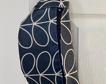 May include: A navy blue fanny pack with a white floral pattern and a zipper closure. The fanny pack is hanging from a white door.