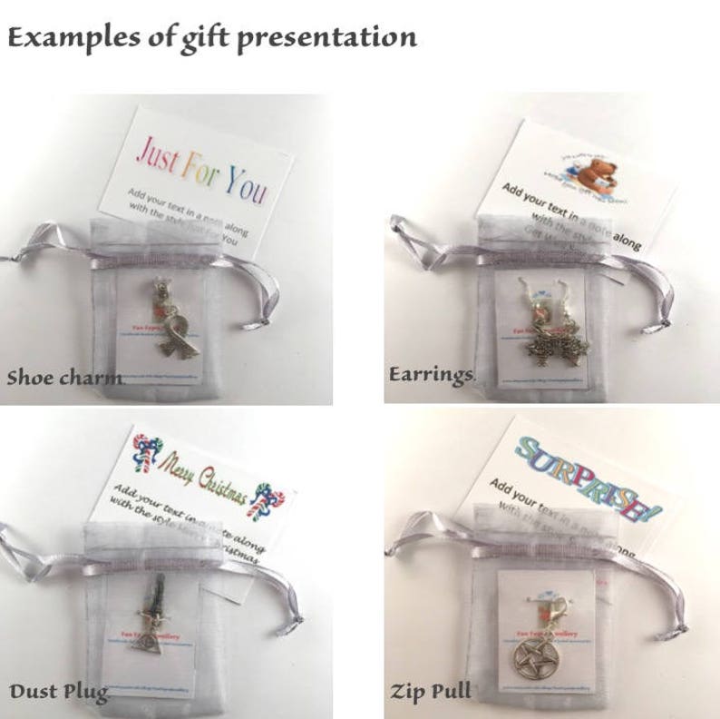 May include: Four examples of gift presentation ideas. Each image shows a small gift in a white organza bag with a card. The cards have different designs and text, including "Just For You", "Merry Christmas", "Surprise!" and a teddy bear. The gifts are a shoe charm, earrings, a dust plug, and a zip pull.