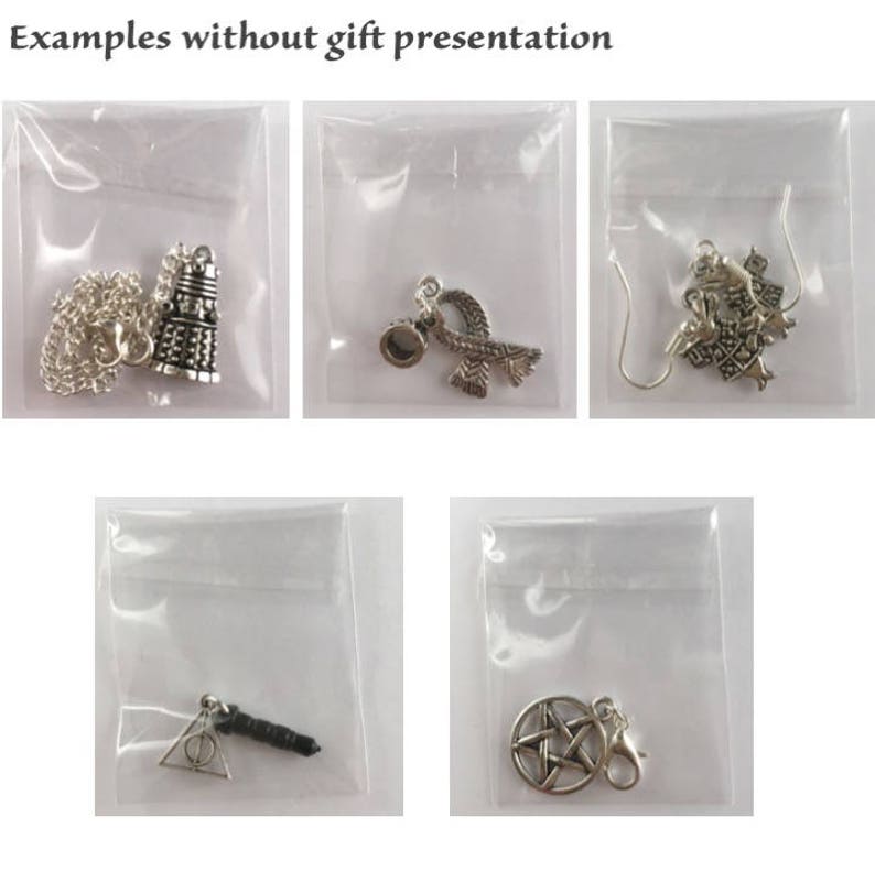 May include: Five silver charm pendants in individual clear plastic bags. The charms include a silver TARDIS, a silver infinity symbol with a silver bead, a silver charm with a detailed design, a silver charm with a triangle and a black wand, and a silver pentagram charm.
