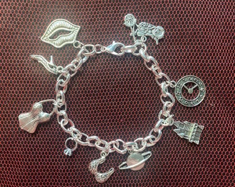 May include: A silver charm bracelet with various charms, including lips, a high heel, a corset, a ring, a planet, a clock, a castle, and a motorcycle.