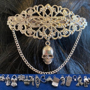 Può includere: Fermaglio per capelli in argento con un design a filigrana e un ciondolo a forma di teschio pendente. Il fermaglio è attaccato a una catena con un ciondolo a forma di teschio.