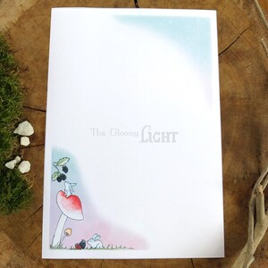 May include: A white rabbit sits on a red mushroom with a white stem. The mushroom is in a forest setting with green leaves and blackberries. The text "The Gloomy Light" is at the top of the page.