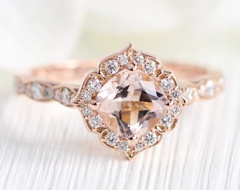 Könnte beinhalten: Ein Verlobungsring aus Roségold mit einem kissenförmigen Morganit-Mittelstück, das von einem Heiligenschein aus kleineren Diamanten umgeben ist. Die Ringschiene ist ebenfalls mit kleineren Diamanten besetzt.