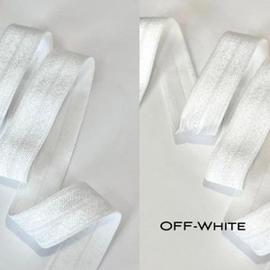 Puede incluir: Dos carretes de cinta el&aacute;stica blanca. El carrete de la izquierda est&aacute; etiquetado como "WHITE" y el carrete de la derecha est&aacute; etiquetado como "OFF-WHITE".