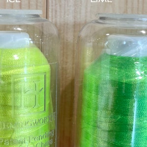 May include: Two spools of thread in clear plastic containers. The spool on the left is a bright yellow-green colour and labelled "Lemon Ice". The spool on the right is a bright green colour and labelled "Brilliant Lime". Both spools are labelled "DMC" and "Patent Pending Made in China."