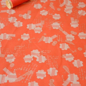 May include: Orange fabric with a white floral pattern. The fabric has a subtle texture and a slightly distressed look. A spool of red thread is lying on top of the fabric.