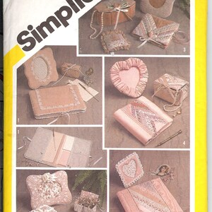 May include: A Simplicity sewing pattern for making a variety of small, decorative boxes and pouches. The pattern includes instructions for making a heart-shaped box, a rectangular box, a round box, and a pouch. The pattern is designed by Marjorie Puckett and is numbered 5296.