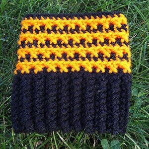 May include: Black and orange crocheted hat with a textured design. The hat has a black band with a repeating pattern of orange and black stitches.