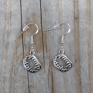 May include: A pair of silver earrings with a detailed design of a set of teeth. The earrings are on a wooden surface.