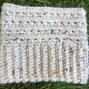 May include: A white crocheted hat with a textured pattern and flecks of brown and gray yarn.