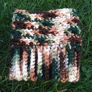 May include: A crocheted cuff in a camouflage pattern with brown, green, white, and beige yarn.