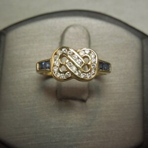 May include: A gold ring with a diamond infinity symbol and blue sapphire accents.