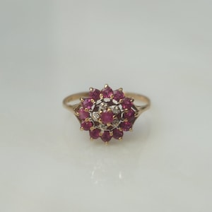 May include: A gold ring with a cluster of red rubies and a few smaller white diamonds in the center.