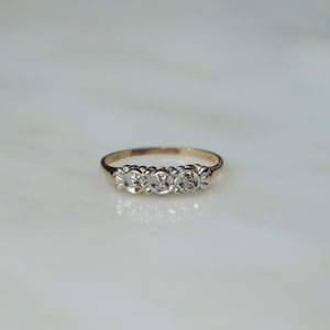 May include: A gold band ring with five round diamonds set in a row.