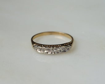 May include: A gold and silver band ring with a delicate floral design.