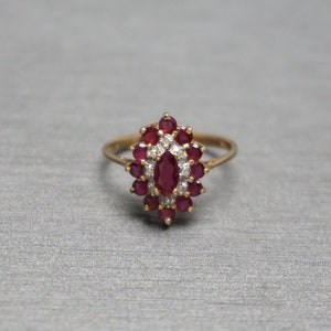 May include: A gold ring with a large red ruby surrounded by smaller red rubies and white diamonds.