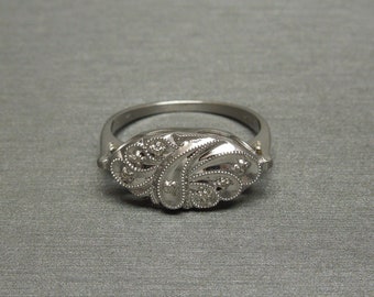 Op de afbeelding: Een zilveren ring met een delicaat bloemmotief bezet met kleine diamanten.
