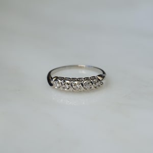May include: A silver band ring with five small diamonds set in a row.