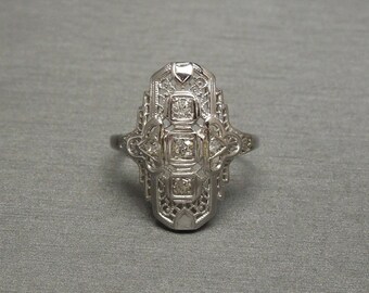 Op de afbeelding: Een zilveren ring met een delicaat filigraan ontwerp en vijf kleine diamanten die in het midden zijn gezet.