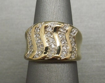 May include: A gold ring with a wide band set with small diamonds in a wavy pattern.