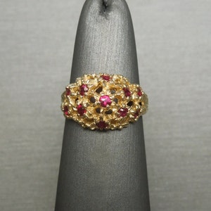 May include: A gold ring with a cluster of red gemstones set in a floral design.