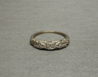 May include: A silver band ring with a row of small diamonds set in a delicate design.