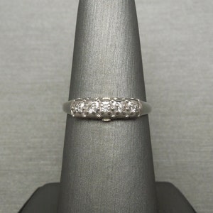 May include: A silver band ring with a row of small, clear diamonds set in a prong setting.