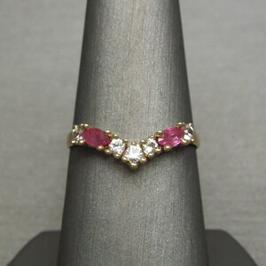 May include: A gold band ring with a V-shaped design featuring alternating pink and white gemstones.