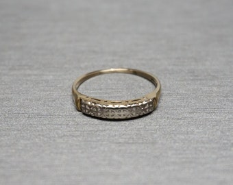 May include: A gold band ring with a decorative design of small diamonds set in a white metal.