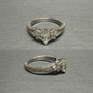 Pode incluir: Uma alian&ccedil;a de noivado de prata com um diamante central em forma de marquise e dois diamantes redondos menores de cada lado. A banda &eacute; decorada com um delicado desenho floral.