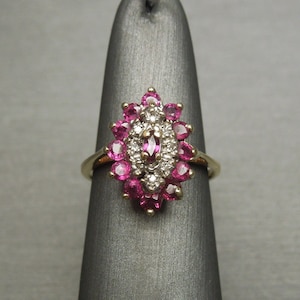 May include: A gold ring with a cluster of pink rubies and white diamonds set in a floral design.