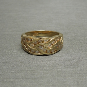 May include: A gold band ring with a braided design set with small diamonds.