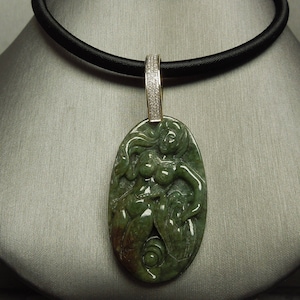 May include: A green jade pendant necklace with a carved figure of a woman. The pendant is set in a gold frame with a diamond-encrusted bail. The necklace is on a black cord.