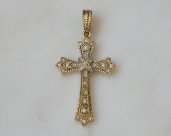 May include: A gold cross pendant with clear crystal accents. The cross has a detailed design with a knot in the center.