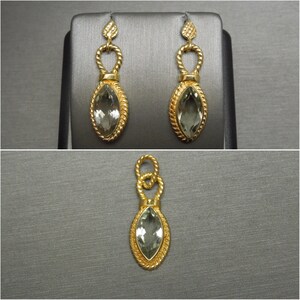 May include: A pair of gold earrings with green gemstone drops. The earrings feature a twisted rope design and a marquise-shaped gemstone.