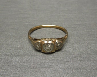 May include: A gold ring with three heart-shaped settings, each containing a small diamond.