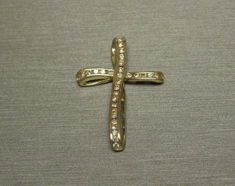 May include: A gold cross pendant with a diamond-encrusted design. The cross is made of a single piece of metal that is twisted and curved to create a unique and elegant look.