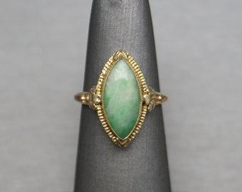 May include: A gold ring with a marquise-shaped green jade stone set in a delicate filigree design.