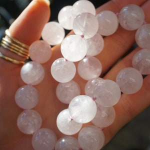 May include: A pink crystal beaded bracelet with a light pink color. The beads are round and smooth, and the bracelet is strung on a clear elastic cord.