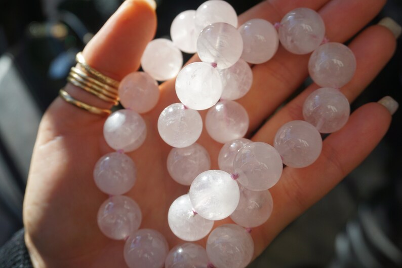 May include: A pink crystal beaded bracelet with a light pink color. The beads are round and smooth, and the bracelet is strung on a clear elastic cord.