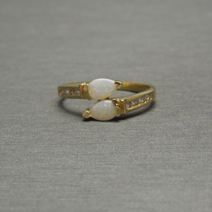 K&ouml;nnte beinhalten: Ein goldener Ring mit zwei birnenf&ouml;rmigen Opalen und einer Reihe kleiner Diamanten.