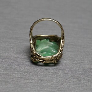 May include: A gold ring with a green jade stone set in a carved design.