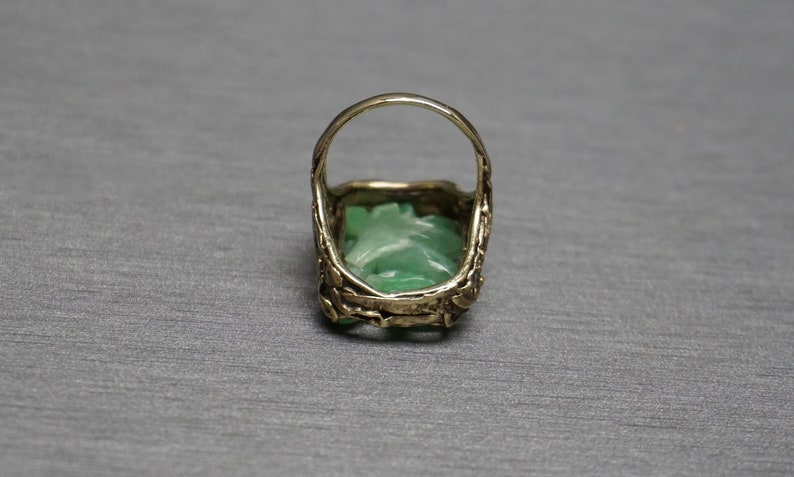 May include: A gold ring with a green jade stone set in a carved design.