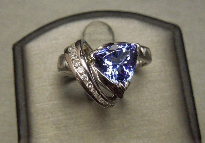 May include: A silver ring with a large, triangular, blue gemstone surrounded by smaller, white gemstones.
